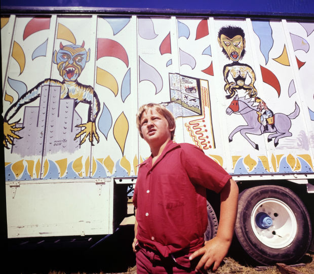 Boy in front of carnival trailer, 1976
